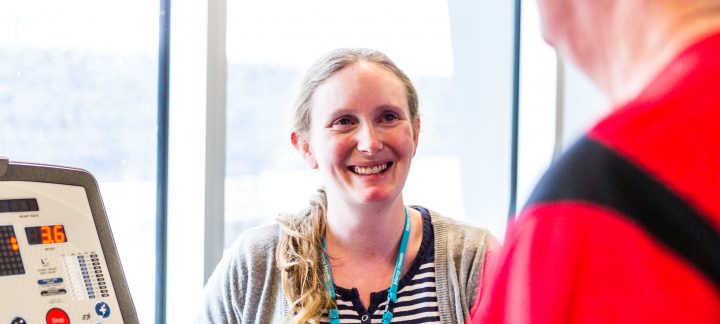 A woman wearing a Mercy Health lanyard smiles at a patient who is on a machine.
